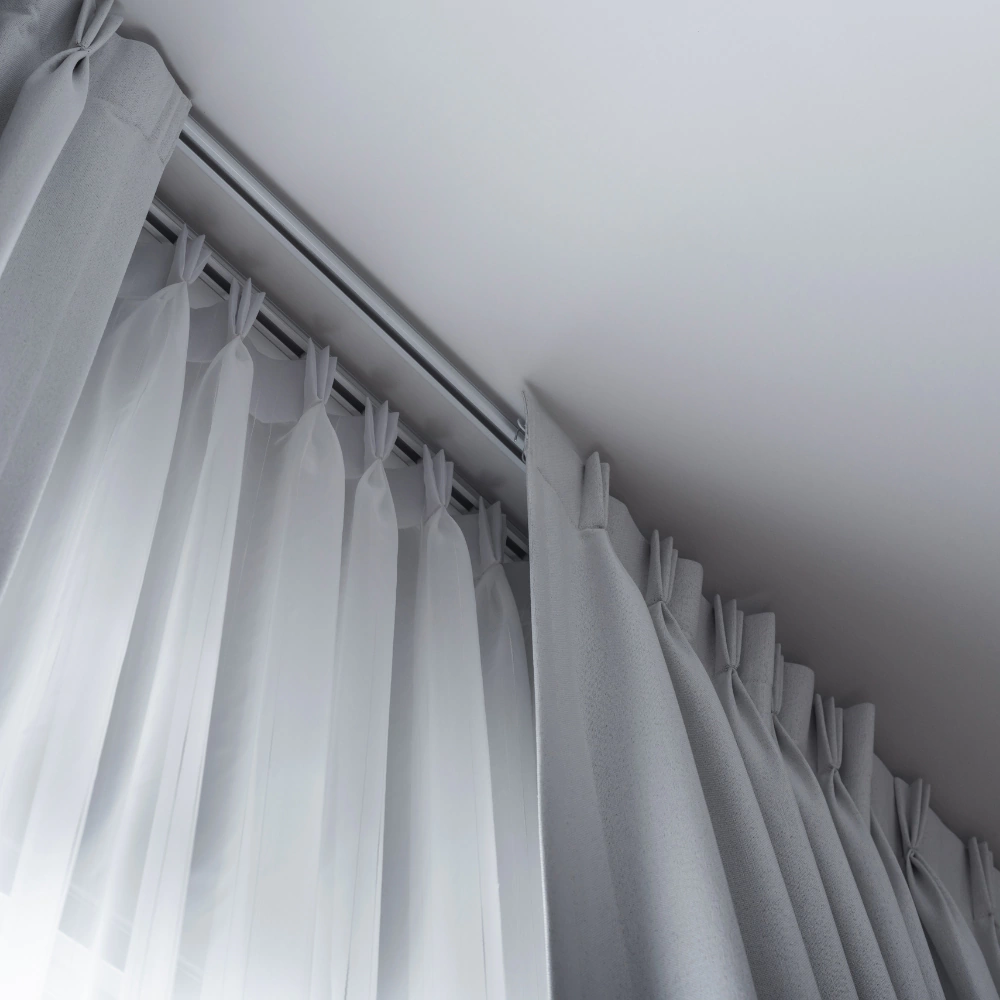 Detalle de riel europeo doble con gasa blanca y cortina gris